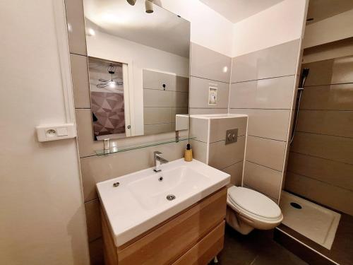 a bathroom with a sink and a toilet and a mirror at Le patio Mézois in Mèze