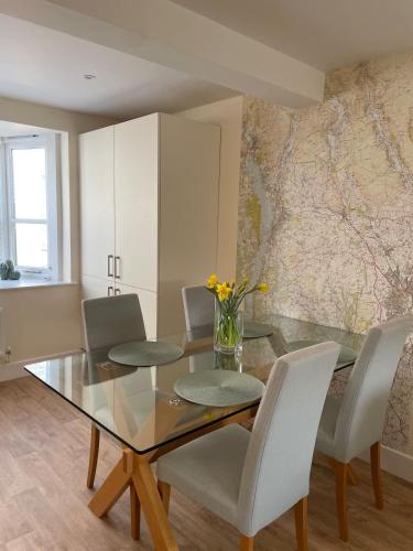 a dining room with a glass table and white chairs at Martindales Yard in Kendal