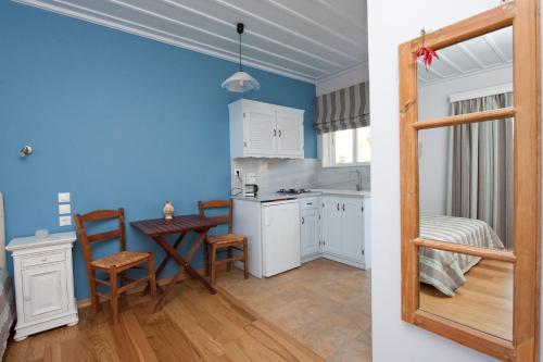 a kitchen with blue walls and a table and chairs at Zorbas Apartments in Volissos