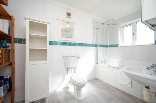 a white bathroom with a toilet and a sink at Spacious 4Bed Home with Decked Garden Forest Hill - Pass the Keys in London