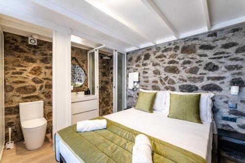 a bedroom with a bed and a stone wall at Social Lodge Galinho House - Sea View - Calheta in Estreito da Calheta
