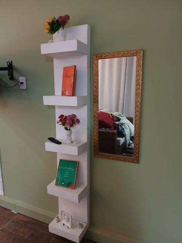 a white book shelf with a mirror on a wall at Aconchego - Centro in Miguel Pereira