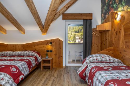 two beds in a room with wooden walls at Pier Hotel in Andalo
