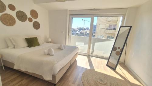 a white bedroom with a bed and a large window at Apartamentos Jardim do Morro in Vila Nova de Gaia