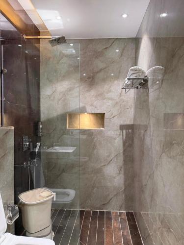 a bathroom with a glass shower with a toilet at Hotel Eastleigh in Ludhiana