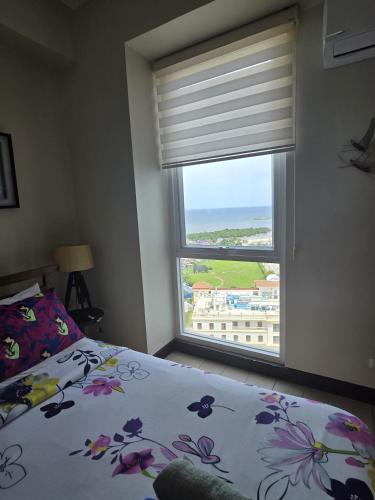 a bedroom with a bed and a window with a view at Mactan Newtown Studio Type with Balcony in Punta Engaño