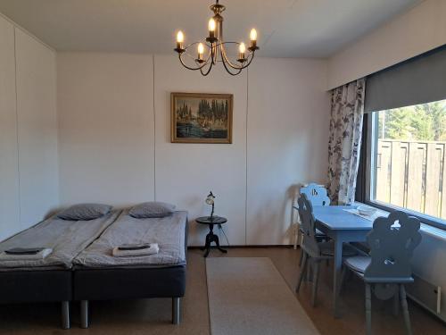 a bedroom with a bed and a table and a window at Koivulehto in Heinävesi