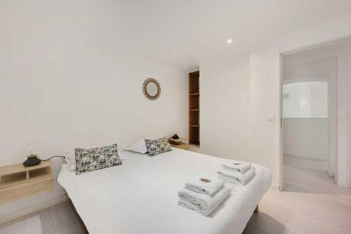 a white bedroom with a bed with towels on it at Spacious apartment-2BR-4P in Le Kremlin-Bicêtre