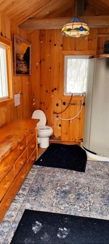a wooden bathroom with a toilet and a refrigerator at Le Chaleureux, Picanoc River in Kazabazua