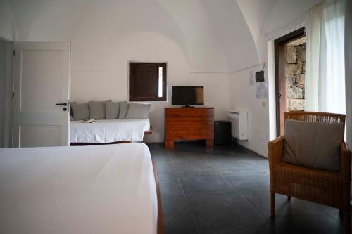 a bedroom with a bed and a tv and a chair at Pantelleria Dream Resort in Pantelleria