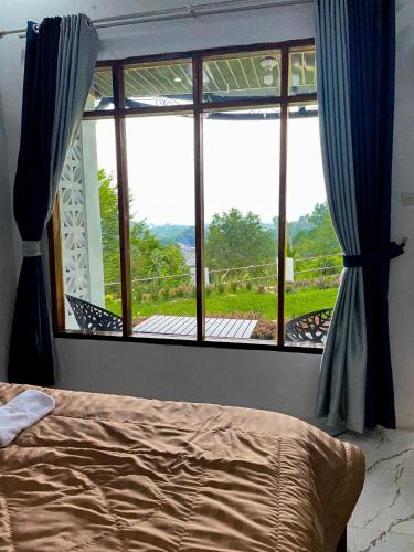 a bedroom with a large window with a view at Nerly's Panorama in Bukit Lawang