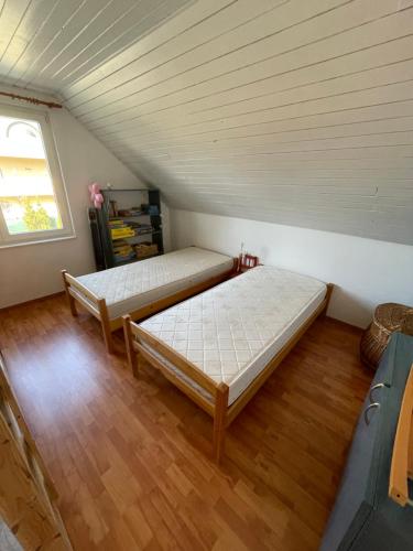 two beds in a room with wooden floors and a window at Residence at lake Balaton in Siófok