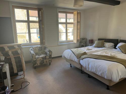 a bedroom with a bed and a chair and windows at The Kings Arms in Cleobury Mortimer