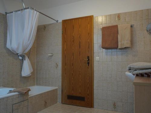 a bathroom with a shower with a wooden door at Ferienhof Kühberg mit schönstem Panoramablick in Blaichach
