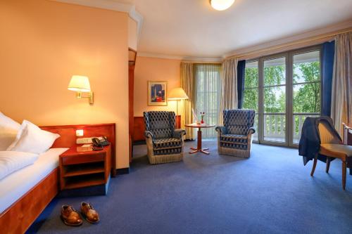 a hotel room with a bed and two chairs and a table at Hotel & Spa Fontenay in Bad Wörishofen