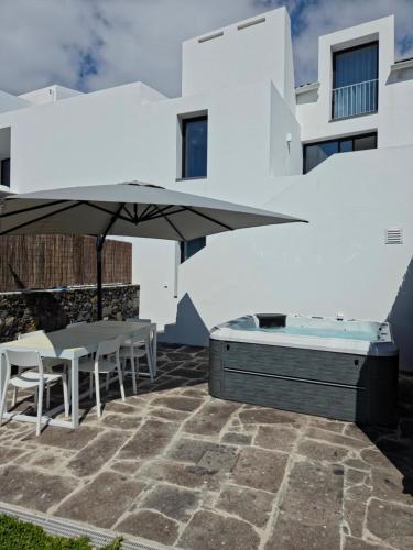 a patio with a hot tub and an umbrella at Oceanside Village 2 in Lagoa