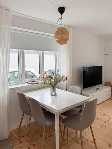 a white dining room table with chairs and a vase of flowers at Nice Nest Boutique Hotel FREE PARKING & 5 min to City Center in Odense
