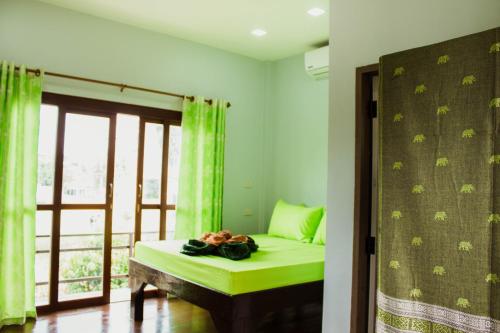 Habitación con cama con cortinas verdes y ventana en Ban Klong Srabua, en Phra Nakhon Si Ayutthaya