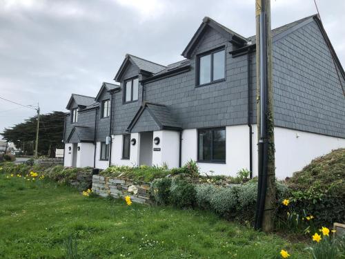 a row of white houses with black roofs at Gwel Owrek in Tintagel