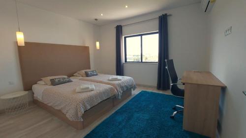 a bedroom with two beds and a desk and a desk at AL Sunset in Albufeira