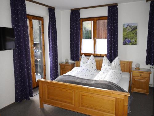 a bedroom with a wooden bed with blue curtains at Ferienhof Kühberg mit schönstem Panoramablick in Blaichach