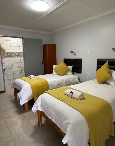a hotel room with two beds with yellow sheets at East Gate Rest Camp in Buitepos