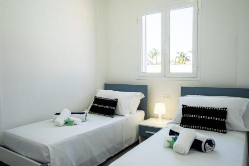 two beds in a room with two windows at Residence Casuzze in Marina di Ragusa