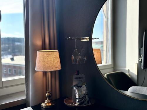 a room with a mirror and a lamp on a table at Hotel Victoria in Skellefteå