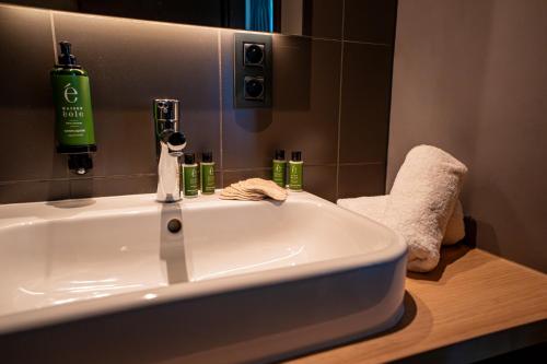 a bathroom sink with a green bottle on top of it at Hôtel & Restaurant Five Nations in Durbuy