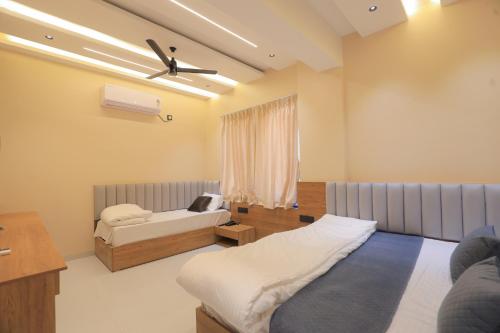a bedroom with two beds and a ceiling fan at Srushti Resort in Daulatābād