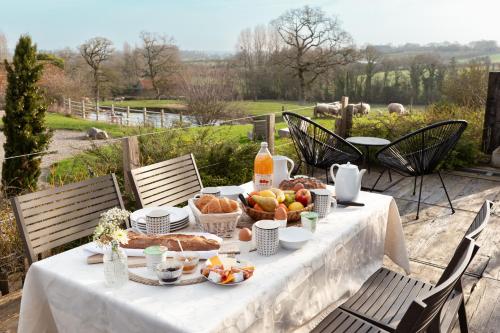 a table with a white table cloth with food on it at Écodomaine le Vérin, Gîtes et spa - Mer, Nature & Confort - Côte d'Opale in Wierre-Effroy