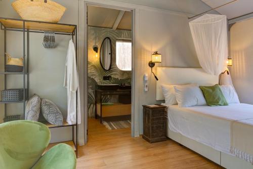 a bedroom with a bed and a chair and a mirror at Amavi Luxury Tent Corfu in Víngla