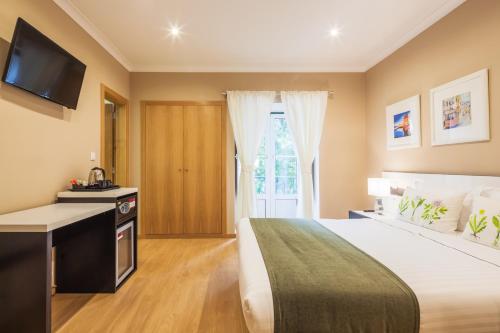 a hotel room with a bed and a television at Vila Nova Guesthouse in Lisbon