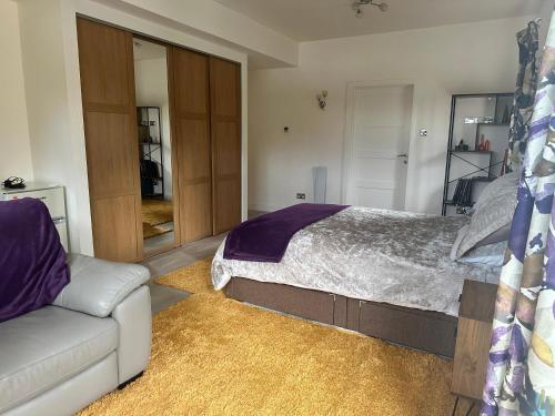 a bedroom with a bed and a couch at Double Ensuite Ground Floor Easy to Cardiff in Cardiff