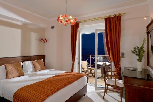 a bedroom with a bed and a desk and a balcony at Ilia Mare in Ilia