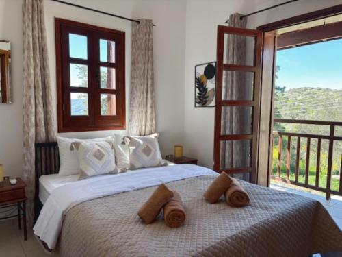 a bedroom with a white bed with a balcony at St Visianos stone house in Philousa