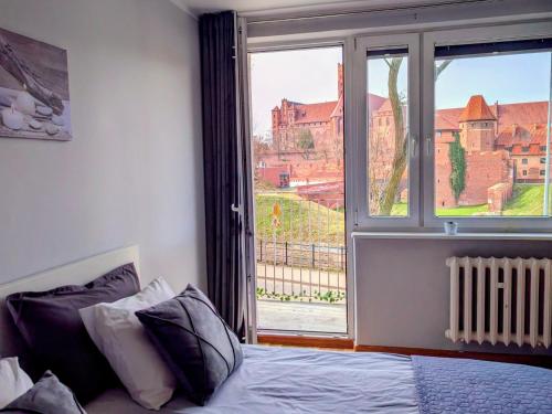 a bedroom with a bed and a large window at Castle View Apartment in Malbork