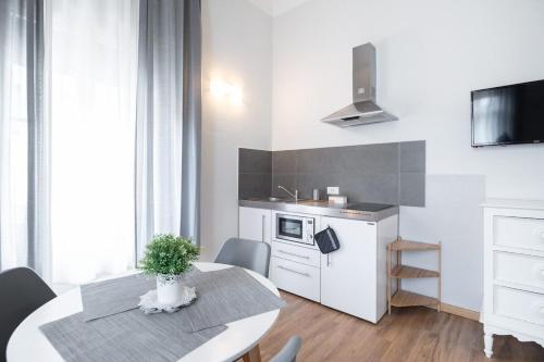 a white kitchen with a table and a kitchen with a sink at Camera Tua - Falloppio 44 Rooms in Padova