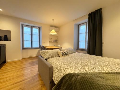 a bedroom with a bed and two windows at Carducci Holiday Home in Chiavenna