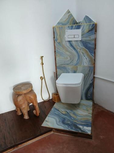 a bathroom with a toilet and a painting on the wall at Juani Pangani in Pangani