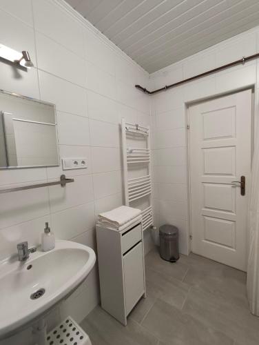 a white bathroom with a sink and a mirror at Fészek Vendégház in Zalaegerszeg