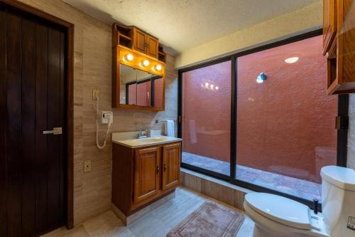 a bathroom with a toilet and a sink and a window at 4000 - Casa San Felipe in Oaxaca City