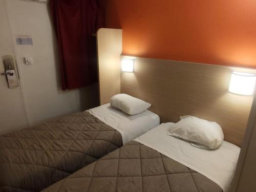 a hotel room with two beds and two pillows at Premiere Classe Agen in Agen