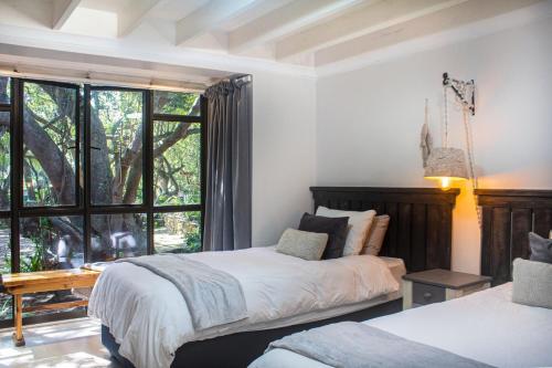 a bedroom with two beds and a large window at The Milkwood House in Wilderness