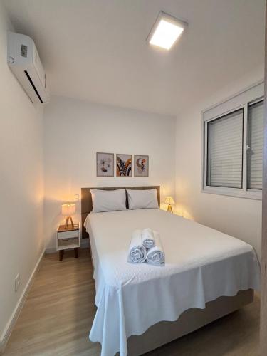 a bedroom with a white bed with towels on it at City Core 2 Bedrooms by AP Smart in Campinas
