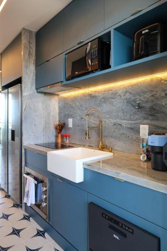 a kitchen with a white sink and blue cabinets at Luxury Flat with Breakfast! in Ipojuca