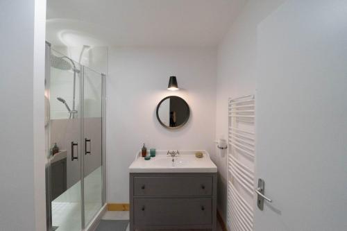 a white bathroom with a sink and a mirror at AppartUnique - Chez Helder - Standing, Calme & Design in Vichy