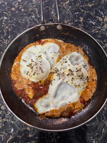 a pan of food with poached eggs on top at Sunset Inn tosh in Tosh