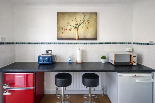 a kitchen with a counter with a microwave and stools at Central Cambridge Fig Tree house in Cambridge