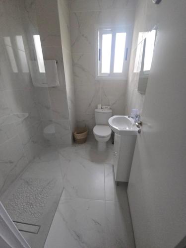 a white bathroom with a toilet and a sink at SunNsea Apartment in Paphos